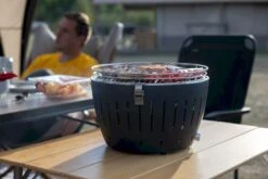 LotusGrill XL Hybrid Houtskoolbarbecue - Rood -Buitenkampeerwinkel lotusgrill in gebruik met toppy shirtje 2